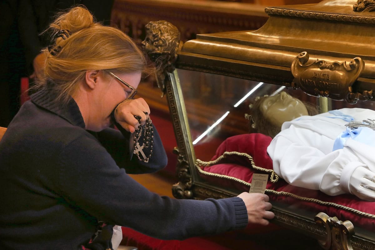 A parishoner becomes emotional as she kneels and prays beside the remains of St. Maria Goretti on Oct. 12 at St. John Cantius Church in Chicago.