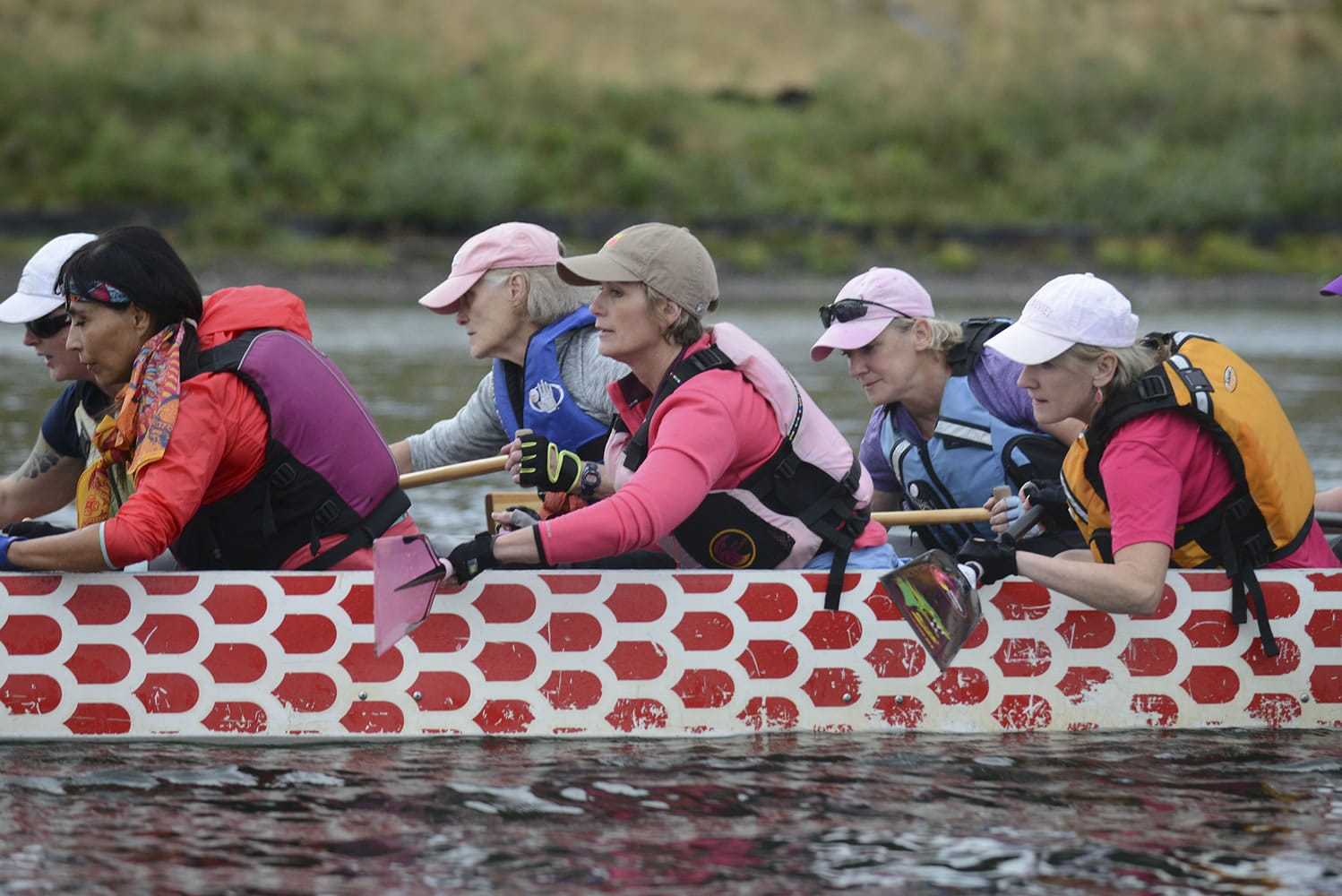 Mary Sullivan, center in orange life jacket, paddles with the Pink Phoenix dragon boat team at a practice on the Willamette River. Like the rest of the team, Sullivan and her twin, Meg Perlick (shown below on the left in purple T-shirt), are breast cancer survivors.