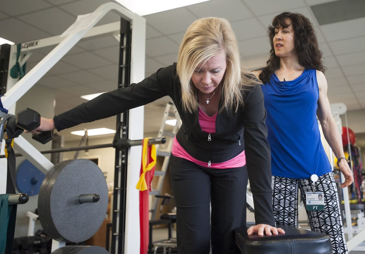 Breast cancer survivor Jill Barr, under the observation of physical therapist Joyce Masters, practices strength-building exercises.
