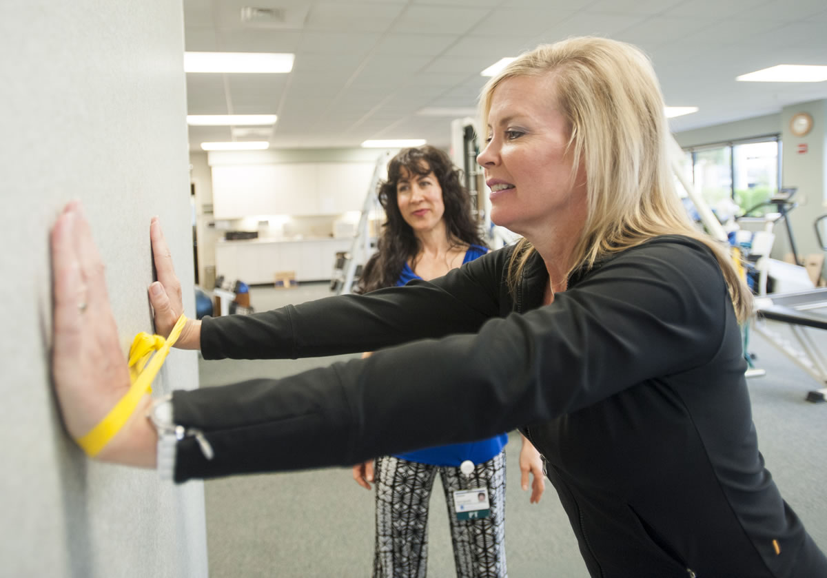 Breast cancer survivor Jill Barr performs a stretching exercise under the observation of physical therapist Joyce Masters. Stretching helps restore range of motion to post-surgical patients.