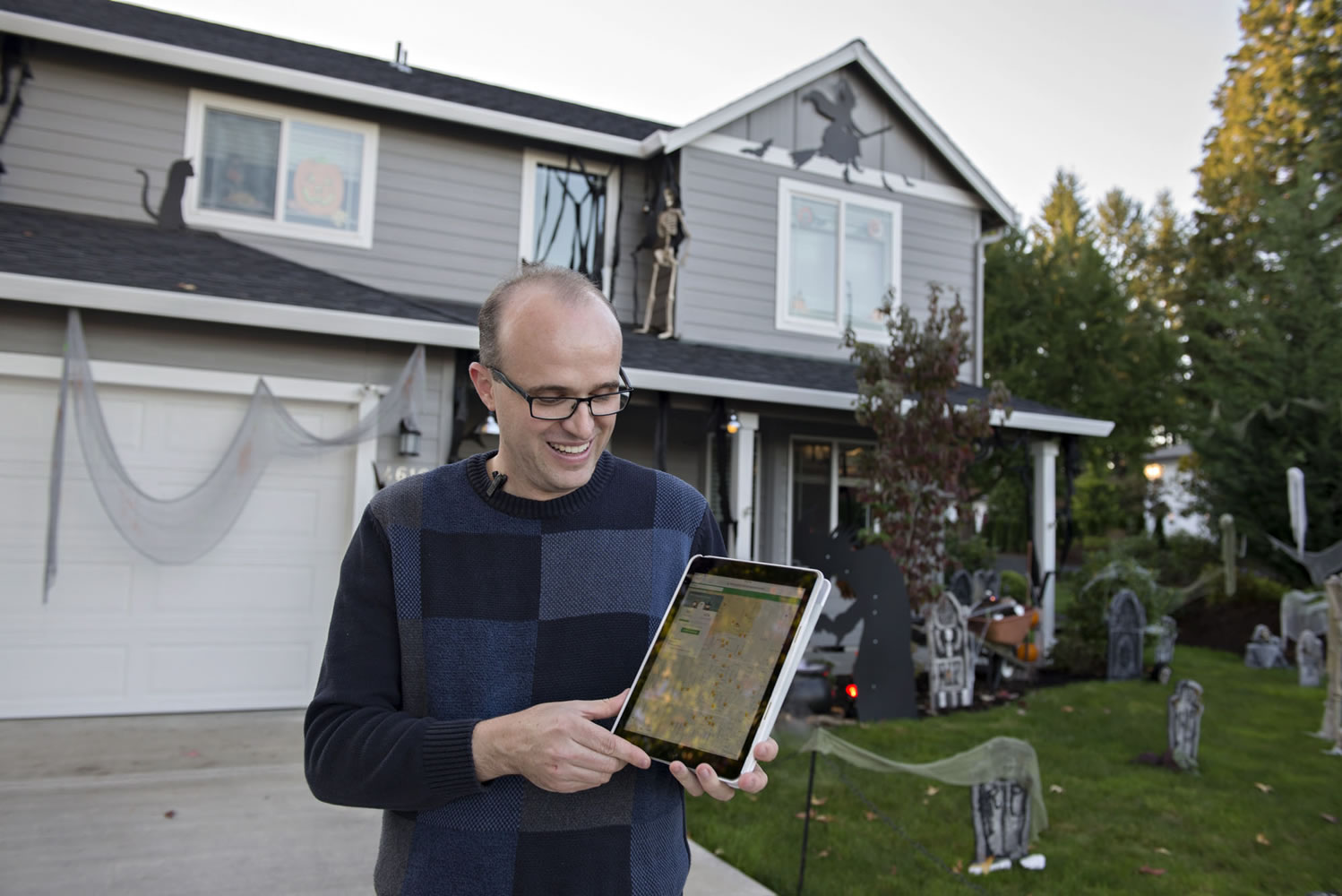 Jim Mains of Vancouver looks over the Nextdoor Treat Map on his iPad outside his home in Northwest neighborhood. People across the county are using the map to mark their homes as trick-or-treat friendly.