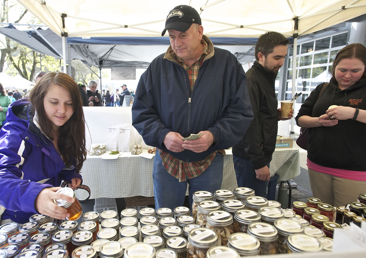 Bill Cole, owner of Nature's Wild Harvest, helps Melanie Kelly of Vancouver choose from a variety of wildflower honey Sunday at the Vancouver Farmers Market.