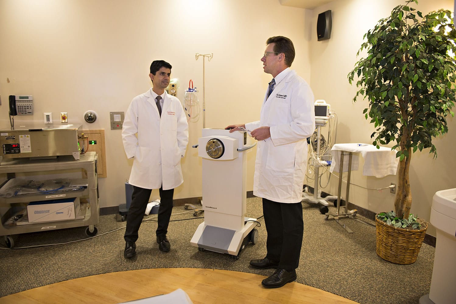Drs. Faisal Siddiqui, left, and Michael Myers discuss a radiation dose plan for a patient while standing near the machine that delivers radiation to patients undergoing breast brachytherapy. Breast brachytherapy delivers radiation through a device placed in the cavity left in a woman's breast after a lumpectomy.