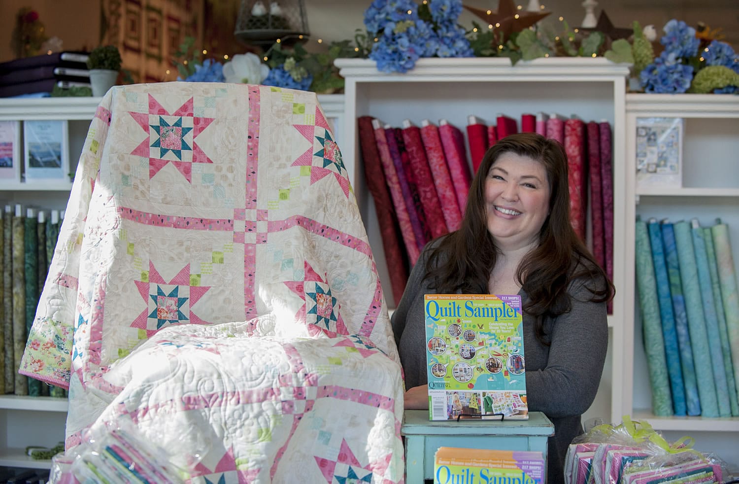 Cheran Bee, owner-operator of Fiddlesticks, shows a quilt that was featured in Better Homes and Gardens Quilt Sampler.