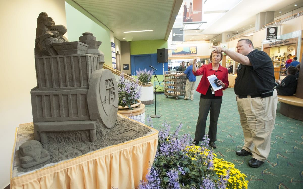 Visitors look at a creation made by sand sculptor Bert Adams of Yacolt. His rendition of Portland International Airport was unveiled Tuesday in the PDX terminal. The Port of Portland, Travel Portland officials, airport employees and visitors marked the 75th anniversary of PDX Tuesday with art displays and cupcakes.