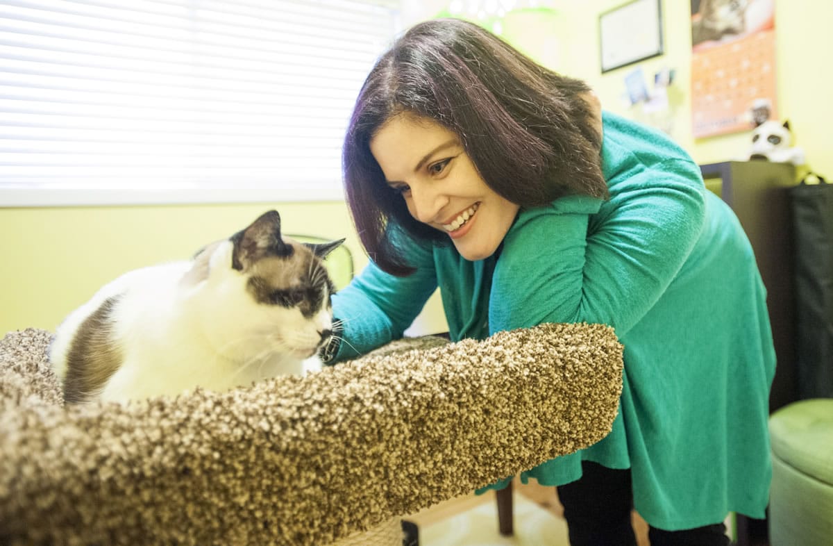 Marci Koski, a certified cat behaviorist, smiles at one of her cats at her home in Vancouver. Koski said her primary goal is to keep cats out of shelters.