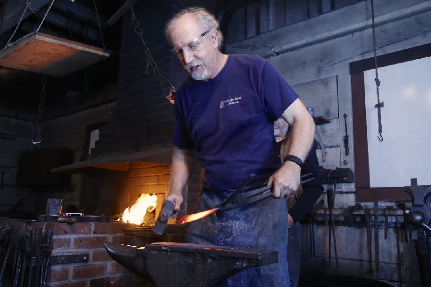 Master blacksmith Jay Close uses a hammer and anvil to flatten metal that will be curved to hold the handle of a garden rake.