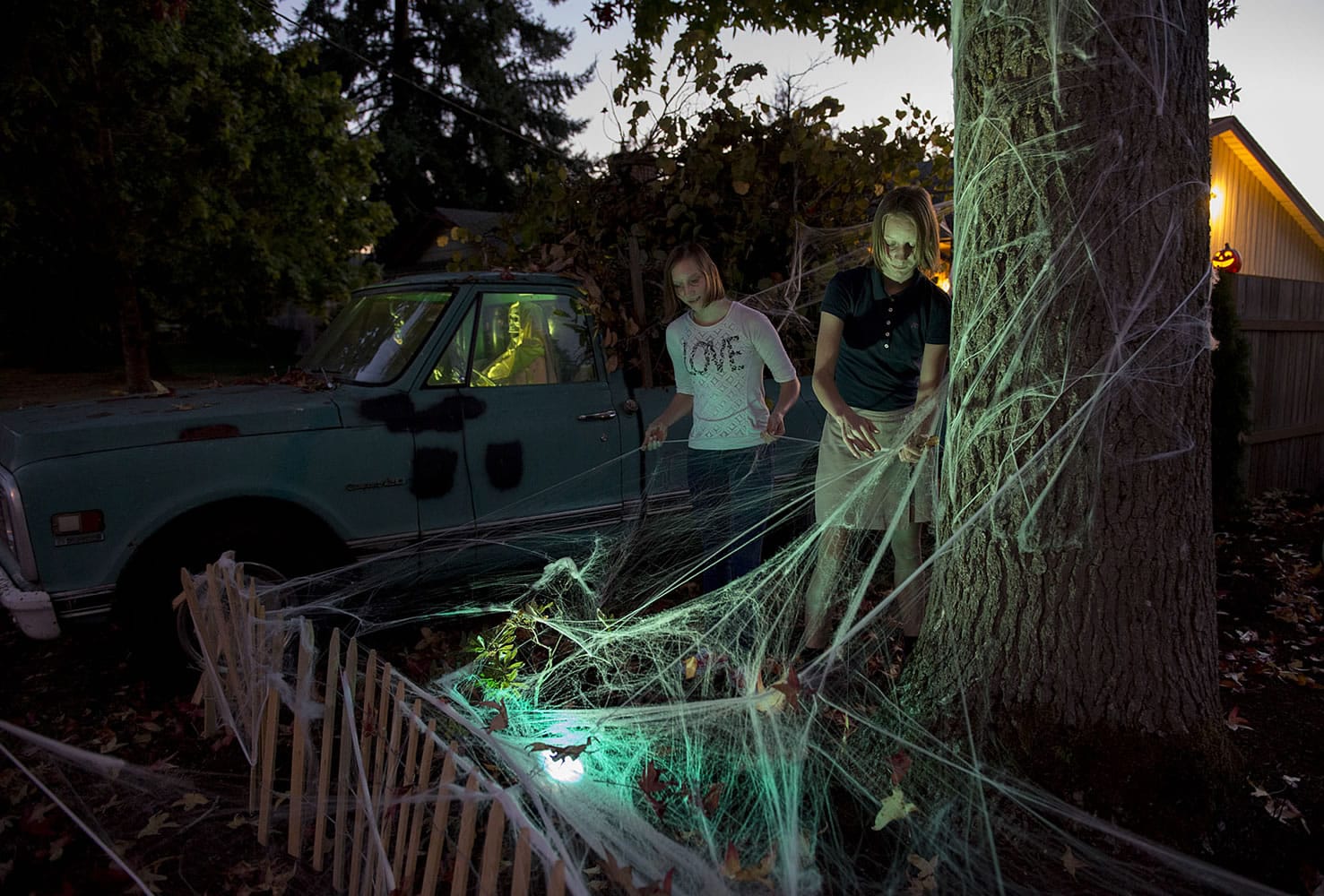 Grace Sherman, left, and her twin sister, Lucy Sherman, both 14, help apply spiderwebs to the exterior of their neighbors&#039; house Tuesday evening in northwest Vancouver.