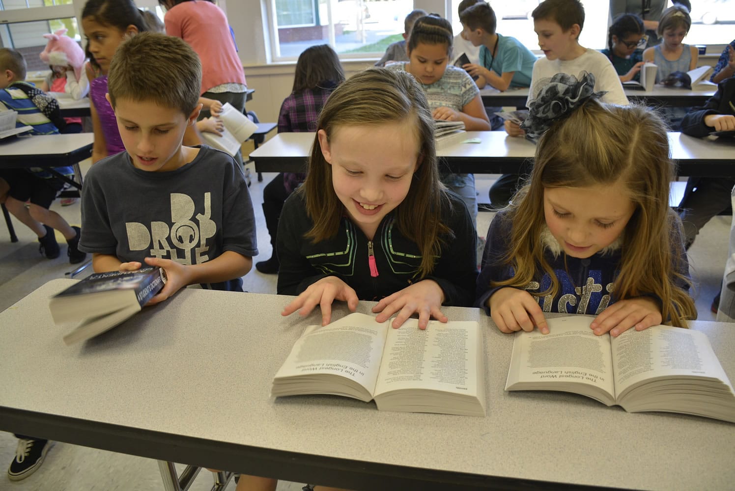Washougal: Gause Elementary School third-graders Cameron Miller, from left, Chloe Baker and Peyton Del Carlo flip through the dictionaries they received from the Camas-Washougal Rotary.