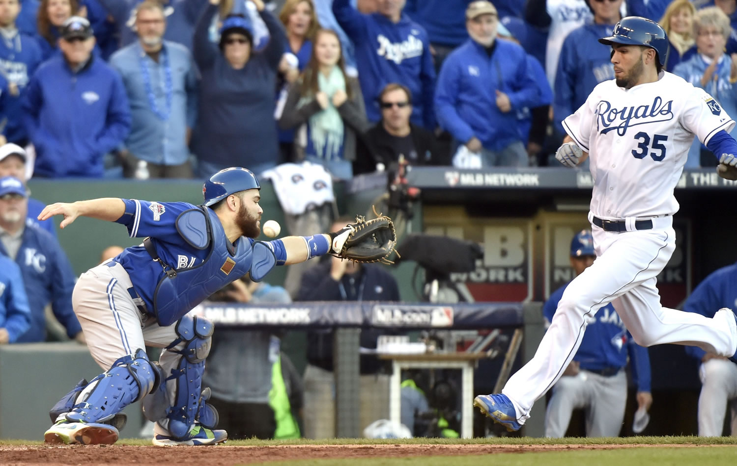 Toronto Blue Jays catcher Russell Martin misses the throw to home plate as Kansas City Royals' Eric Hosmer, right, comes in to score during the seventh inning in Game 2 of baseball's American League Championship Series, Saturday, Oct. 17, 2015, in Kansas City, Mo.