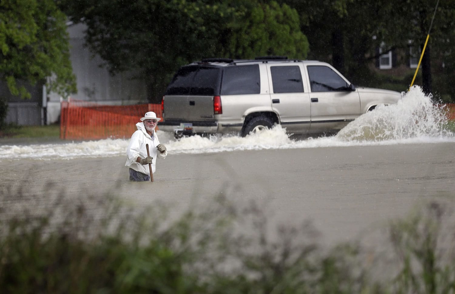 Floodwaters rise as a vehicle and a man navigate flooded streets Sunday in Florence, S.C.