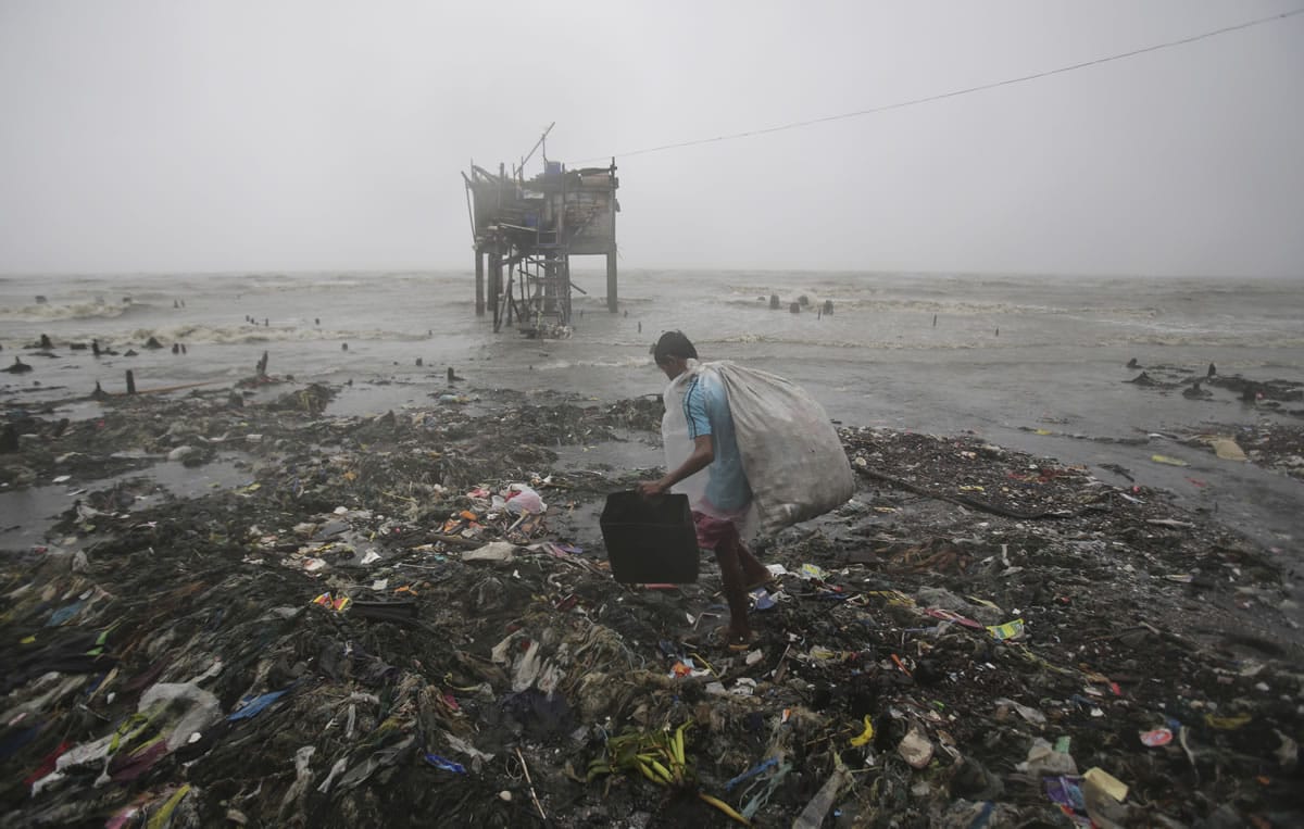 A Filipino man scavenges recyclable materials near a house on stilts by the bay Sunday as strong winds and rains caused by Typhoon Koppu hit the coastal town of Navotas, Philippine. The slow-moving typhoon blew ashore with fierce wind in the northeastern Philippines early Sunday, toppling trees and knocking out power and communications.
