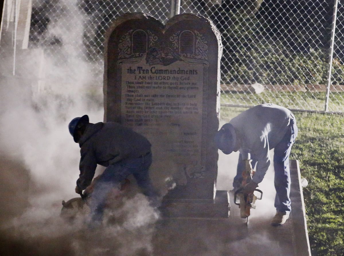 Workers remove the Ten Commandments monument from its base on the grounds of the state Capitol in Oklahoma City on Monday. The removal comes after the Oklahoma Supreme Court&#039;s decision in June that the display violates a state constitutional prohibition on the use of public property.