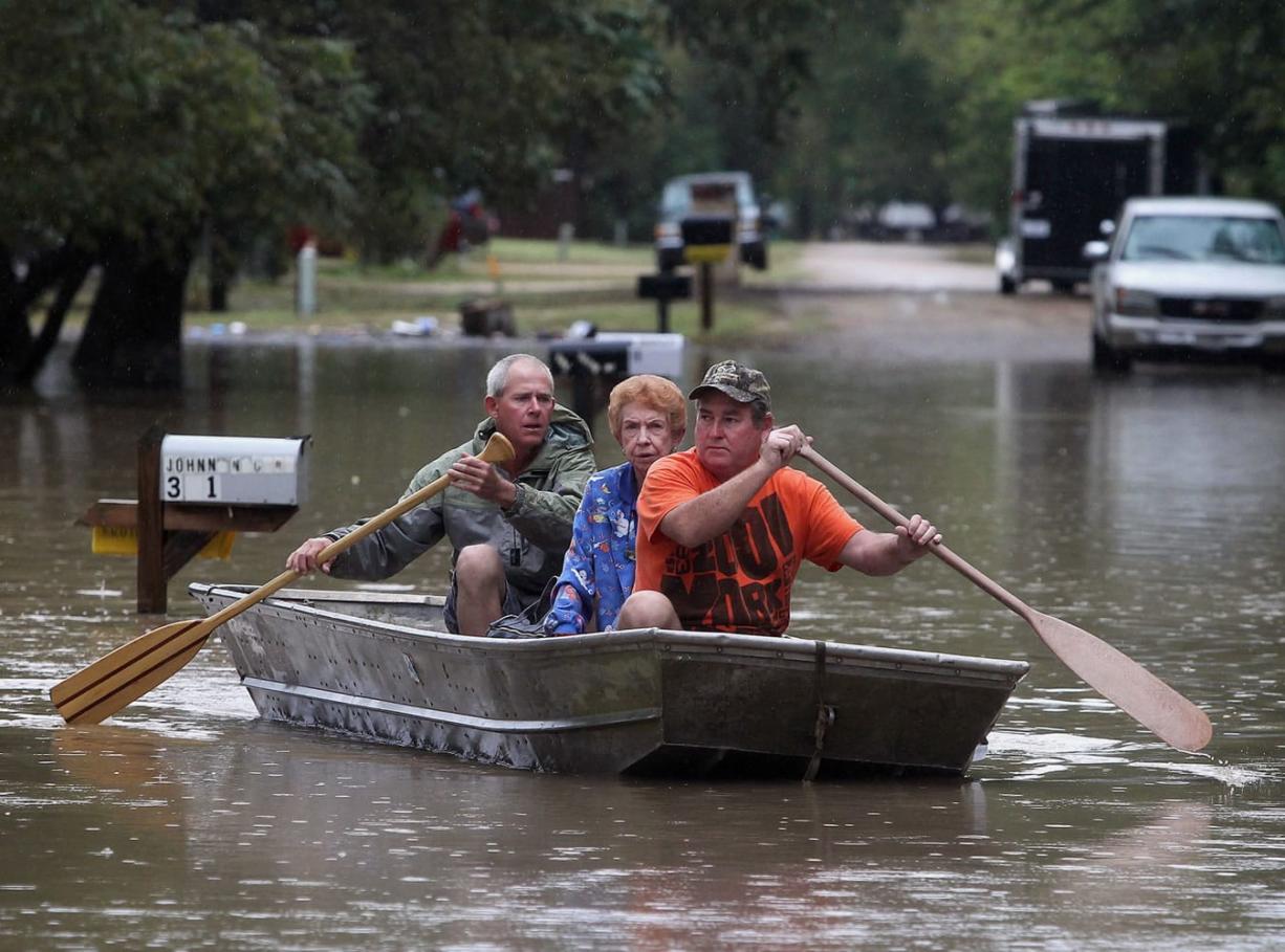 J.B. Neckar, right, and his brother Johnny Neckar, left, paddle their mother Gelene Neckar, center, from her flooded home near Downsville, Texas, Saturday, Oct. 24, 2015. Heavy rains have forced parts of the Brazos River out of its banks and endangering homes located in the small community just outside of Waco, Texas, according to the Waco Tribune Herald.