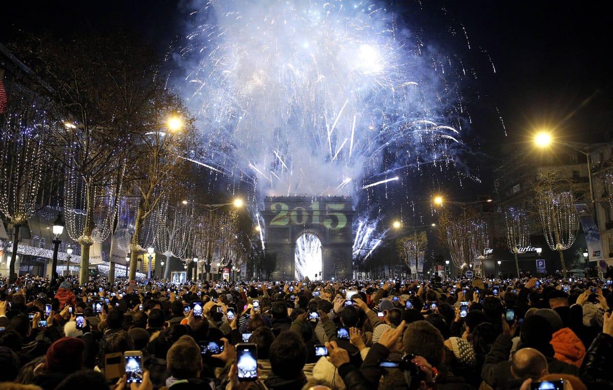 Revellers photograph fireworks over the Arc de Triomphe as they  celebrate the New Year on the Champs Elysees avenue in Paris, France.