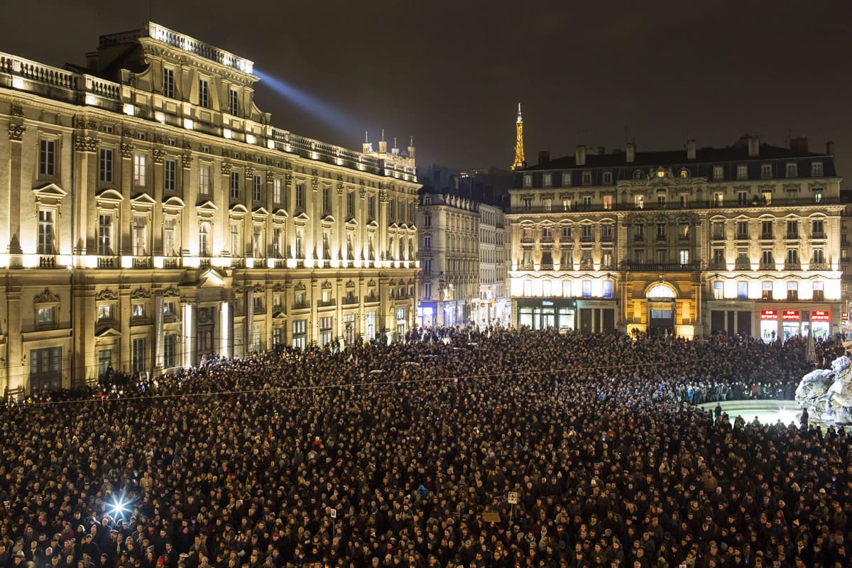 Thousands of people gather for a moment of silence Wednesday to pay their respects to the victims of the deadly attack at the Paris offices of French satirical newspaper Charlie Hebdo, in Lyon, central France. Masked gunmen stormed the Paris offices of a weekly newspaper that caricatured the Prophet Muhammad, killing at least 12 people, including the editor, before escaping in a car.