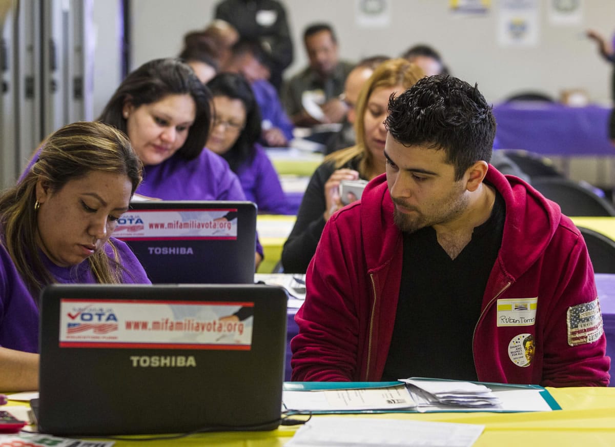 A health care workers union member Kathy Santana, left, assists Ruben Torres, 27, with health care enrollment Monday in Commerce, Calif.