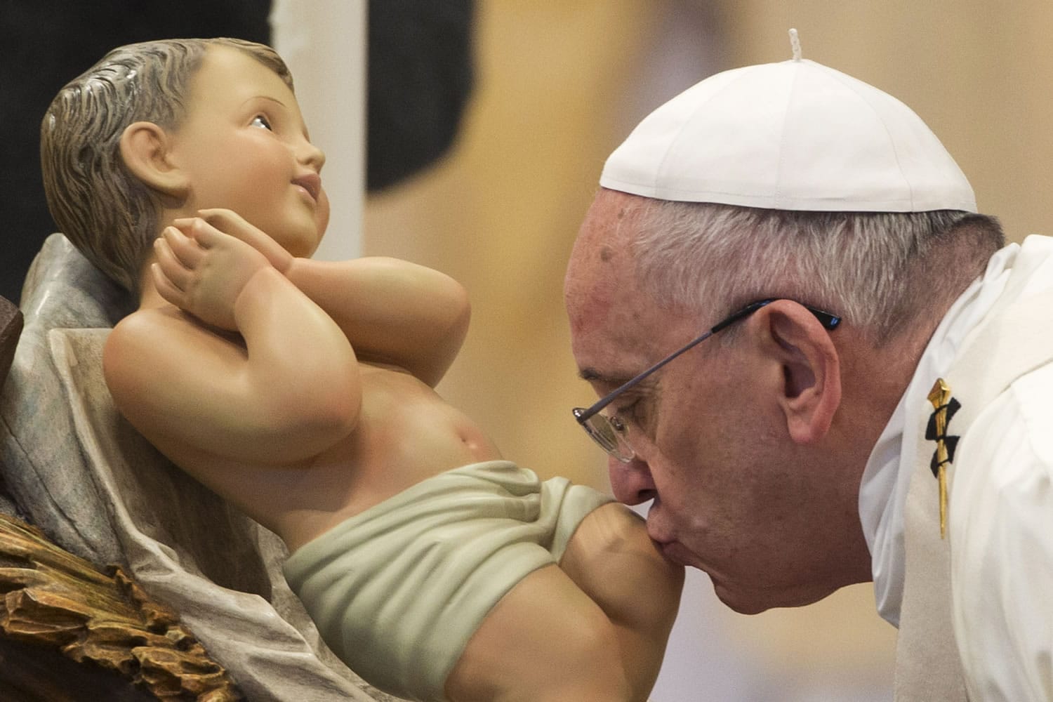 Pope Francis kisses a statue of the baby Jesus as he arrives to celebrate a New Year mass Thursday in St.