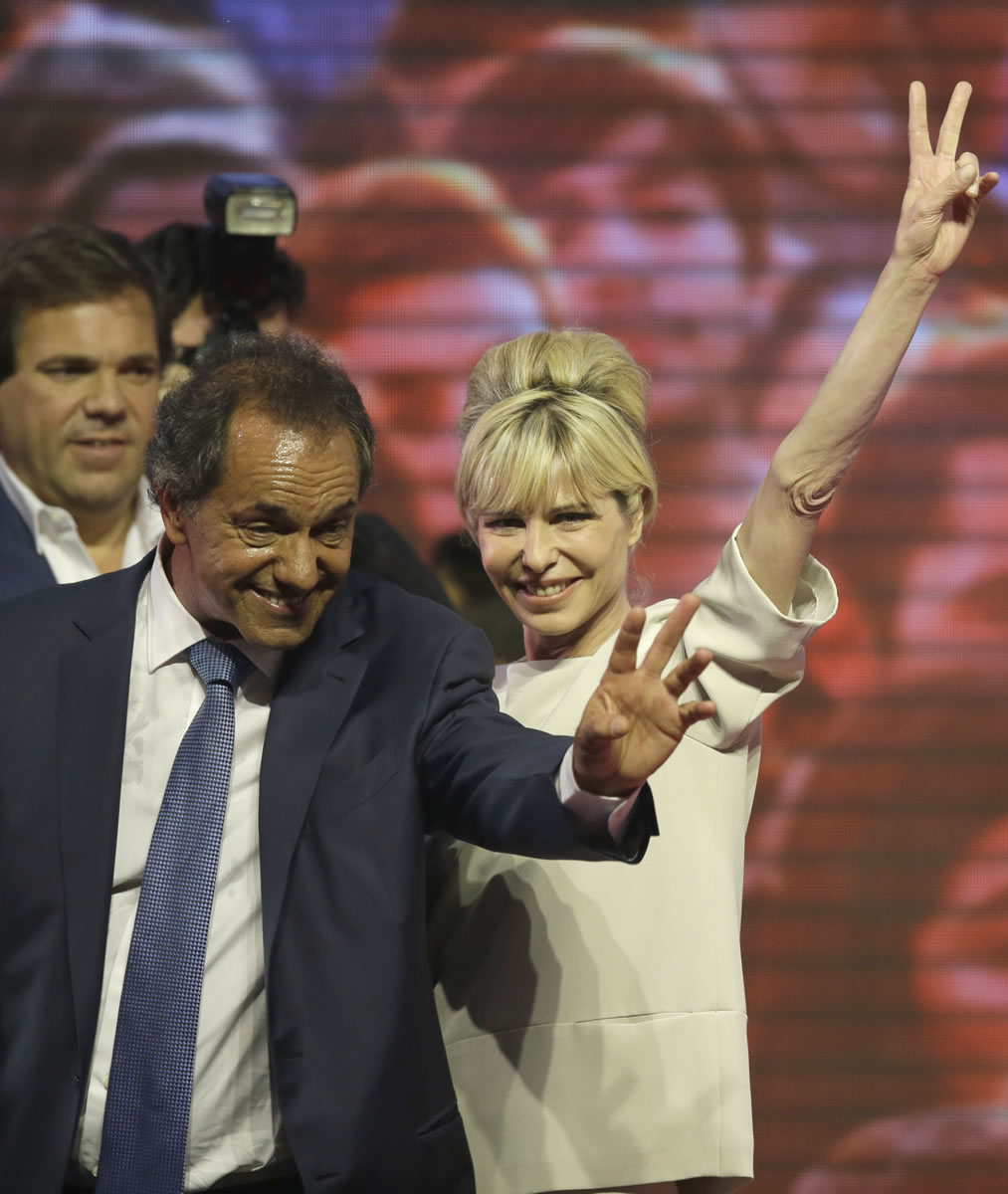 Accompanied by his wife, Karina Rabolini, Buenos Aires&#039; Governor and ruling party presidential candidate Daniel Scioli, left, greets supporters Sunday at Luna Park in Buenos Aires, Argentina.