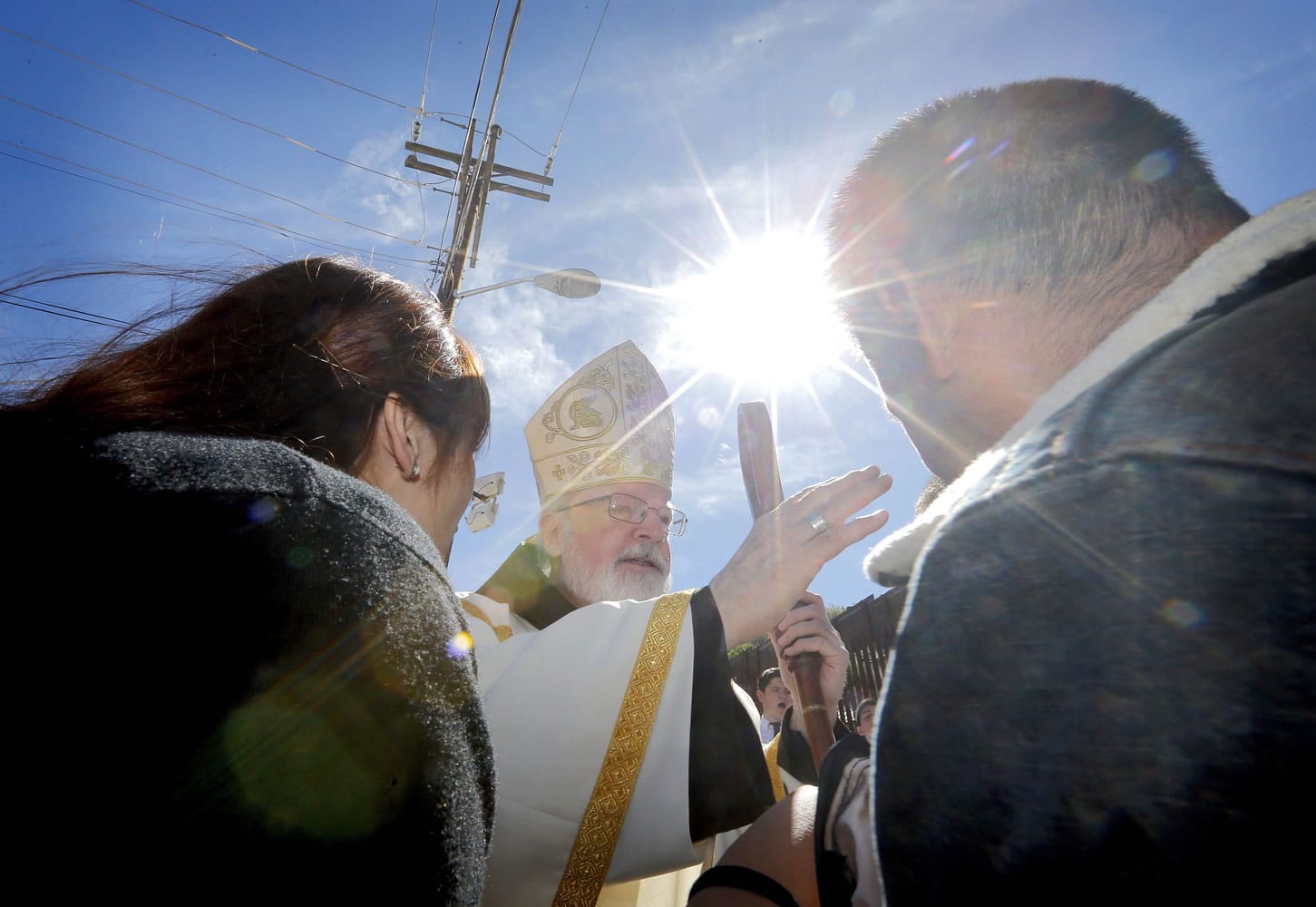 Cardinal Sean O'Malley blesses a family after mass Tuesday along the international border wall in Nogales, Ariz.
