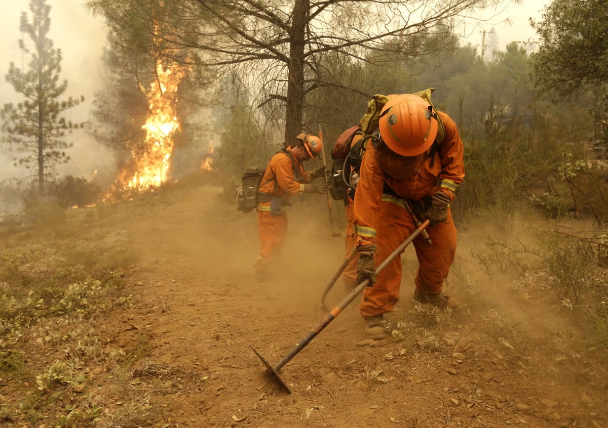 A California Department of Corrections and Rehabilitation inmate work crew builds a containment line ahead of flames from a fire near Sheep Ranch, Calif. California officials are considering allowing inmates with violent backgrounds to work outside prison walls fighting wildfires. Currently only minimum-security inmates with no history of violent crimes can participate.