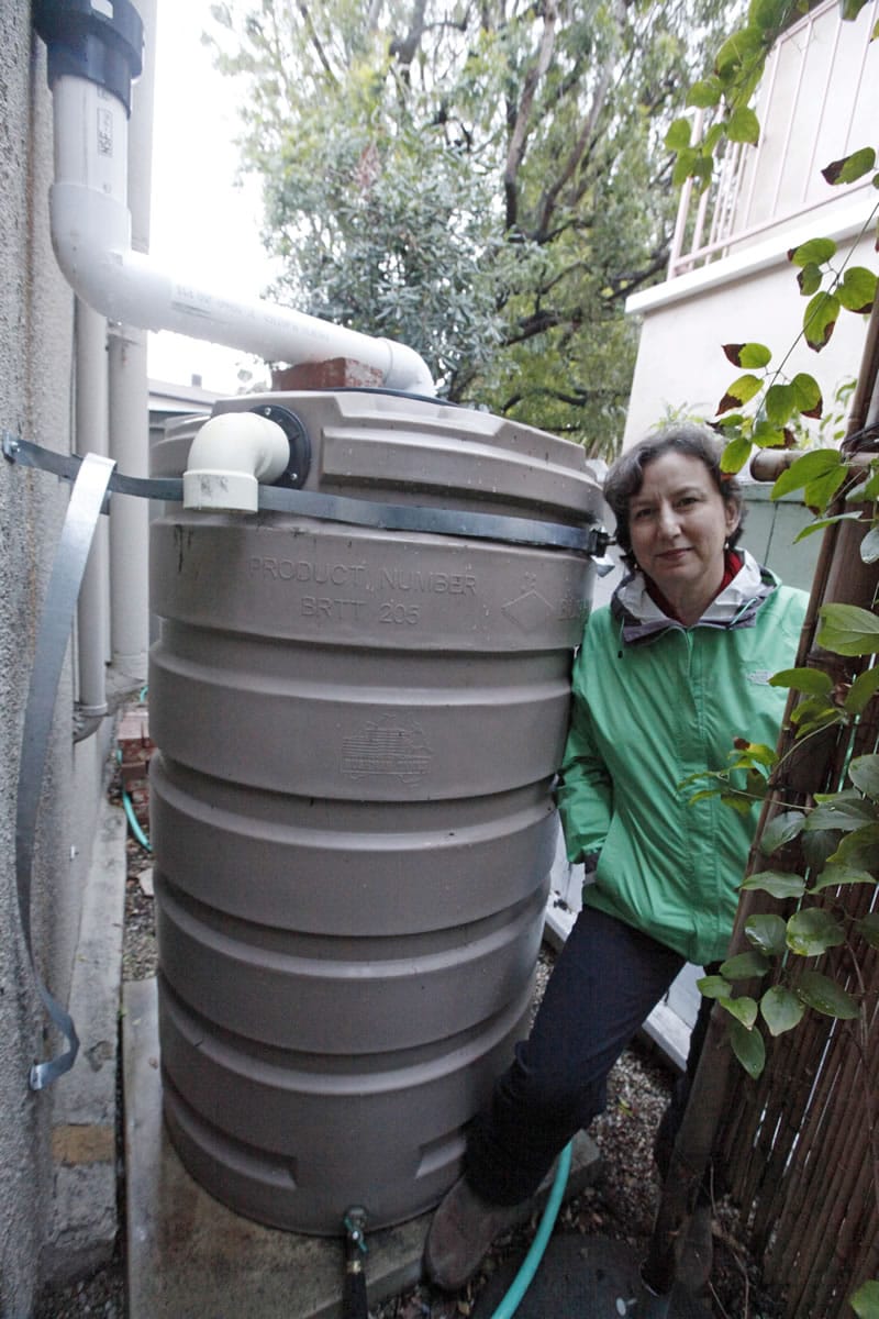 Santa Monica, Calif., resident Josephine Miller stands next to her 200-gallon water storage tank that collects rain from her home's roof to water her garden.