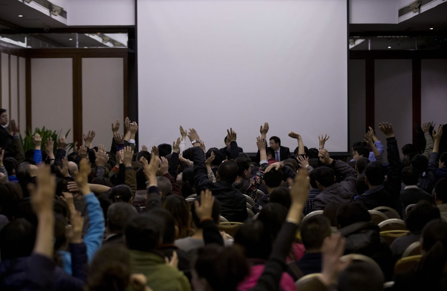 Relatives of Chinese passengers aboard the missing Malaysia Airlines Flight MH370 raise their hands to question Malaysian government officials during a news briefing held by the airlines at a hotel ballroom in Beijing on Monday.