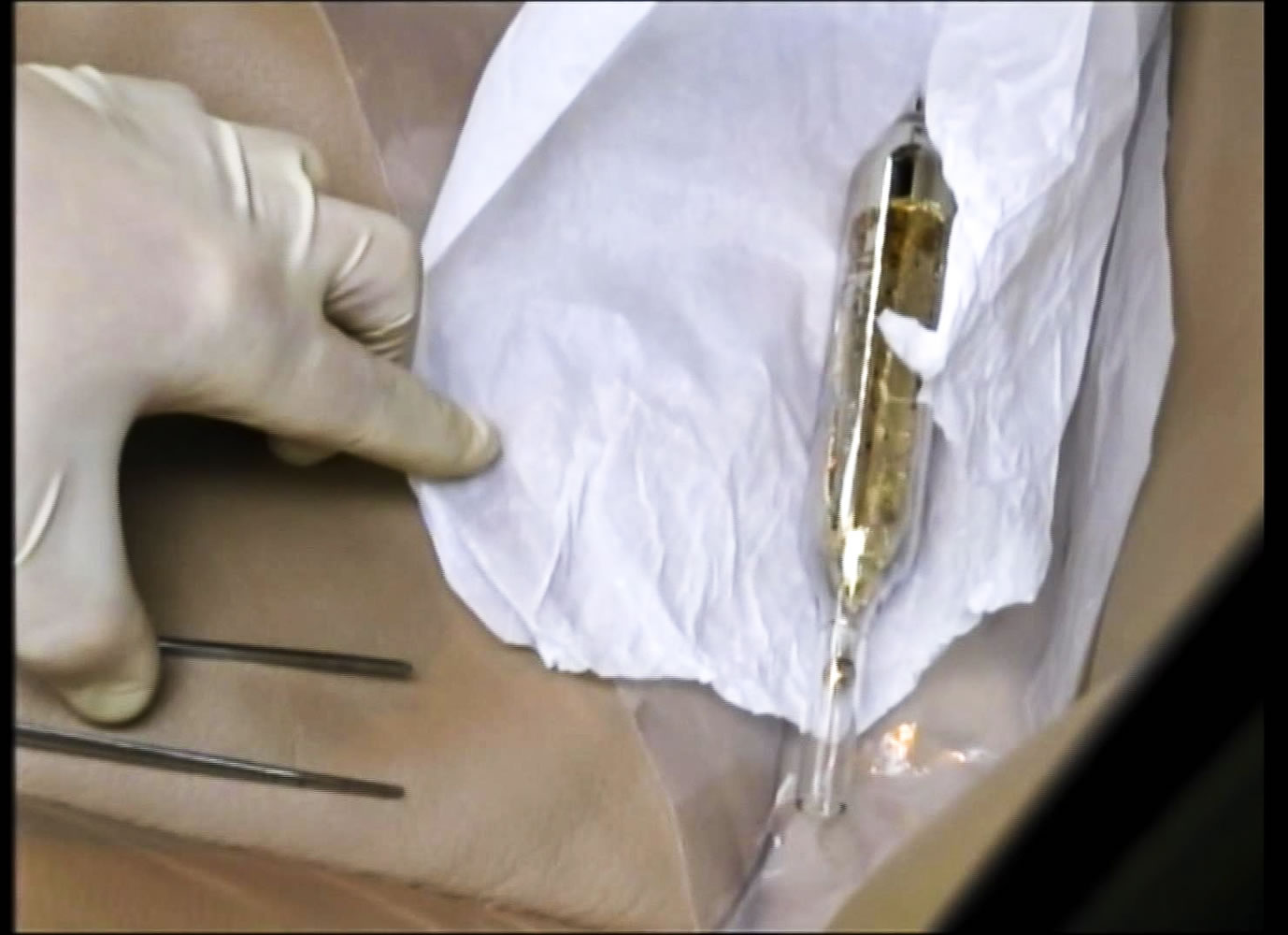 In this Feb. 19 image from video, an investigator shows a vial containing cesium-135 on the seat of Valentin Grossu&#039;s car following his arrest in Chisinau, Moldova.