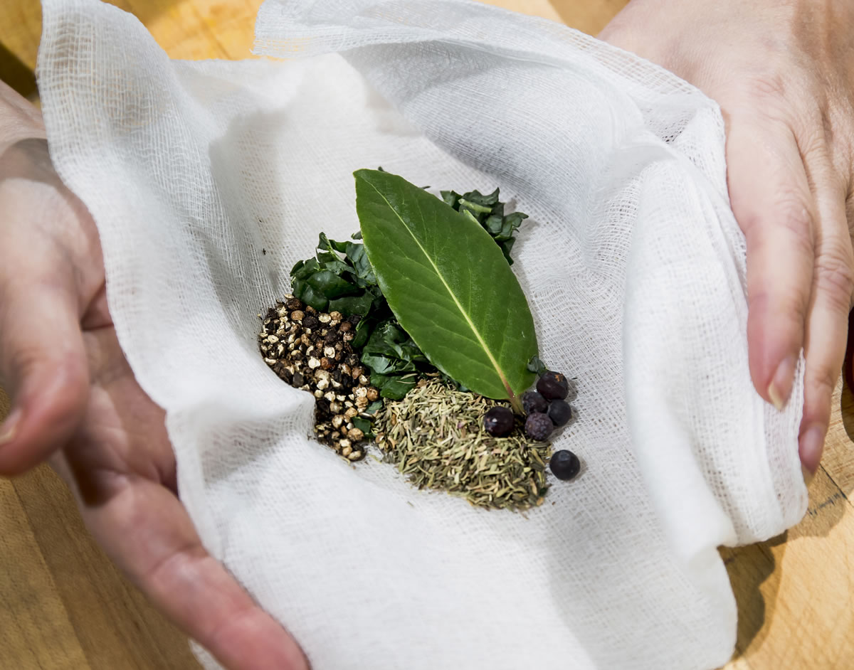 Start by bundling the spices and herbs, parsley, thyme, peppercorns, bay leaf and juniper berries, in cheesecloth.