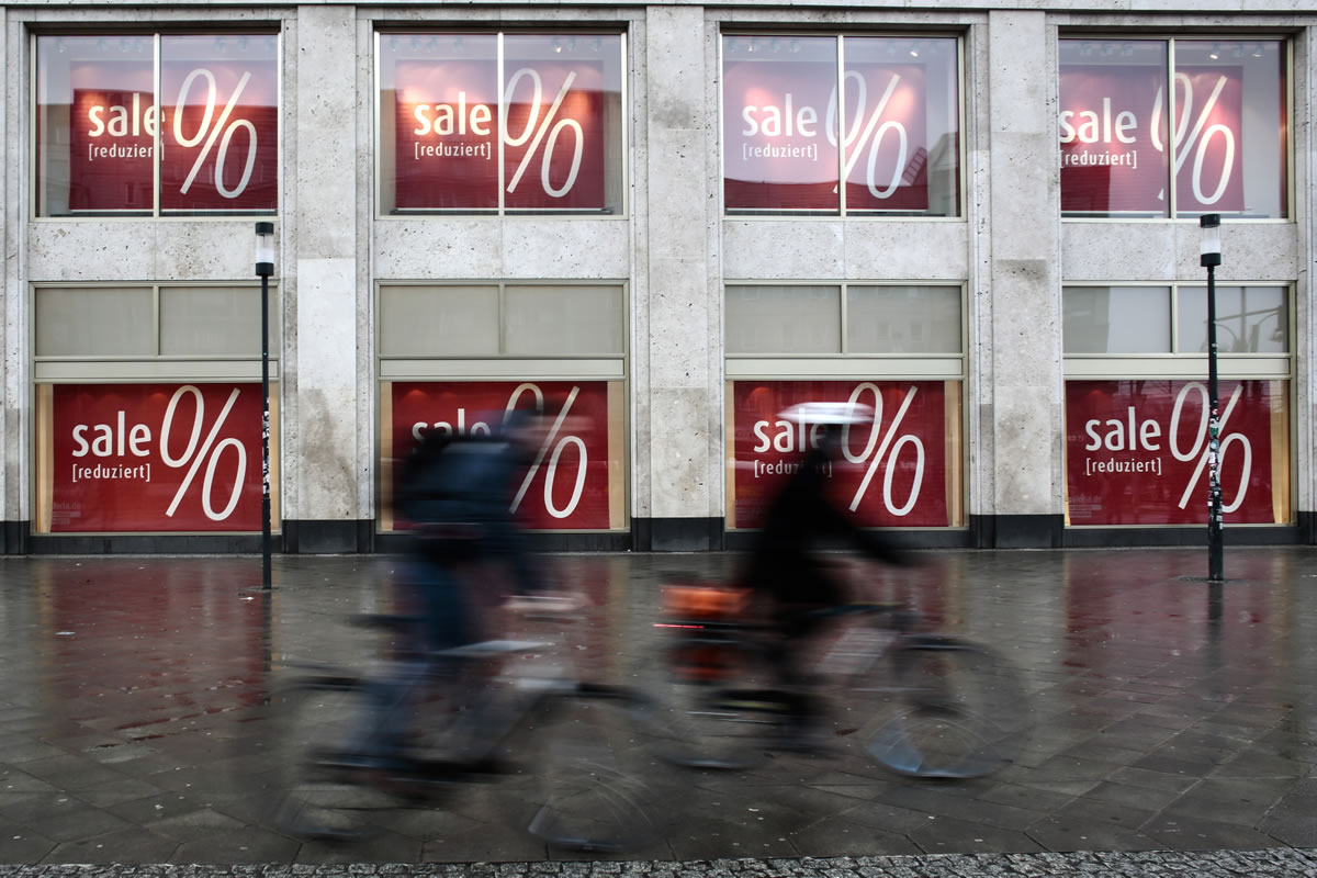 Bicycle riders pass sales posters displayed at a department store in Berlin, Wednesday, Jan. 7, 2015.  Plunging energy costs have caused consumer prices in the eurozone to fall annually for the first time since 2009, official figures showed Wednesday, in a development that's likely to reinforce market expectations that the European Central Bank will soon provide an aggressive monetary stimulus. In its flash estimate of inflation, Eurostat, the EU's statistics agency, said consumer prices in the 18-country eurozone were 0.2 percent lower in December than the previous year. The decline was bigger than anticipated. The consensus in markets was for a 0.1 percent fall. The main reason behind the slide from the 0.3 percent inflation rate recorded in November was the plunging oil price, which has been most noticeably been passed on to consumers at the pump.