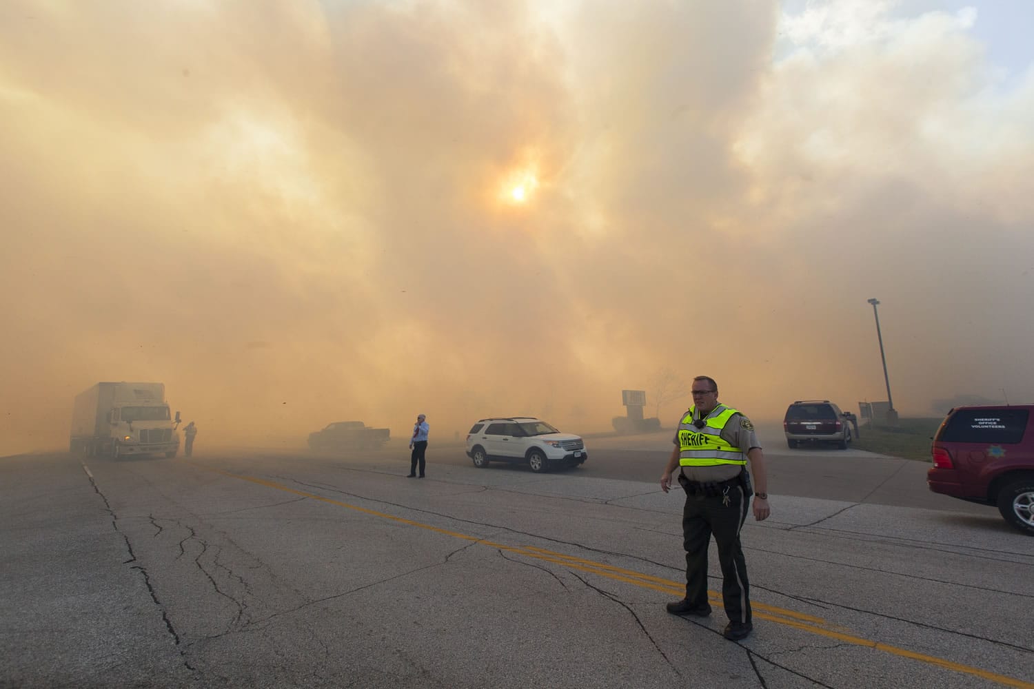 Authorities direct traffic through heavy smoke from a burning field Monday in Eldridge, Iowa.