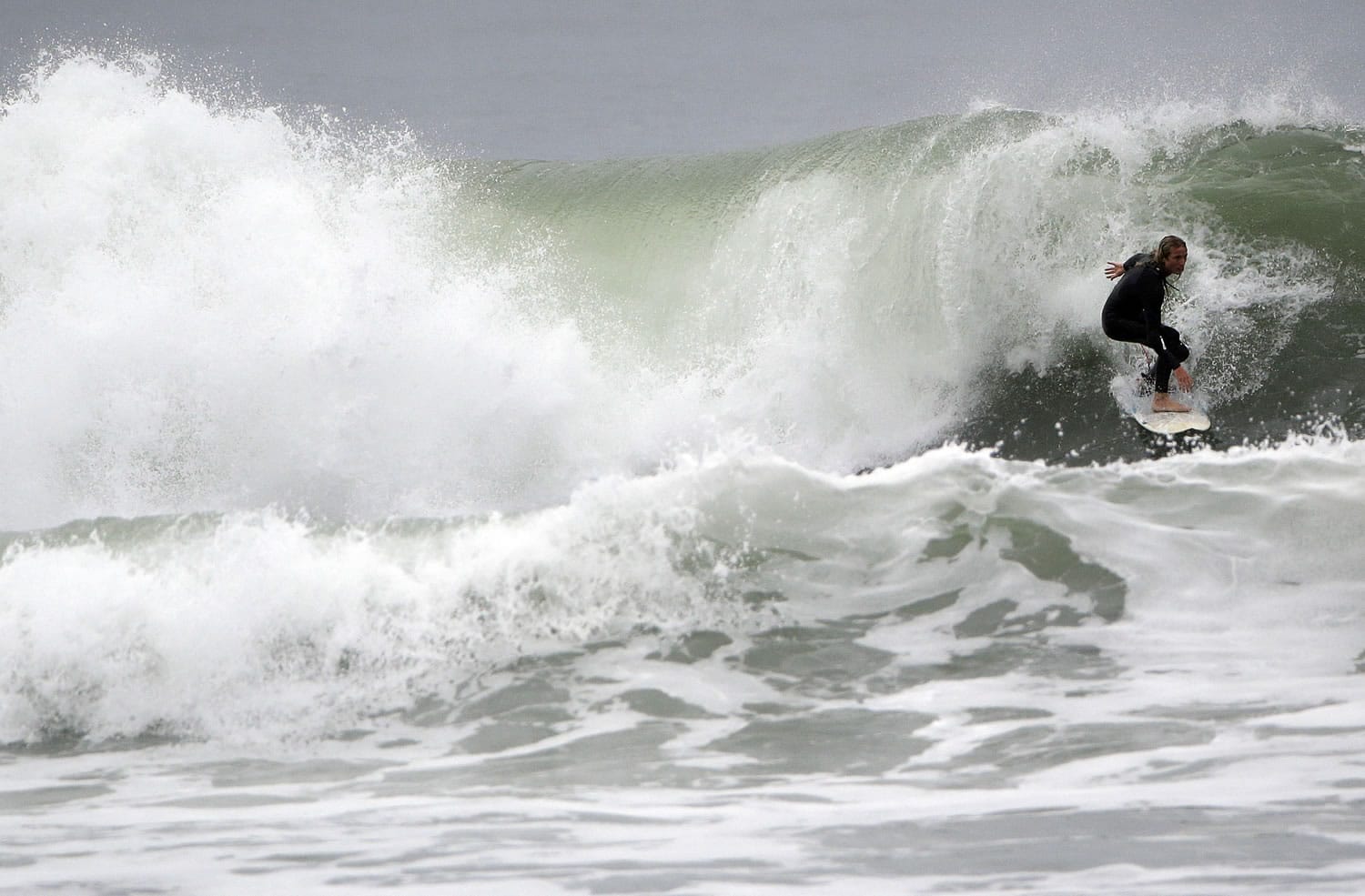 A surfer negotiates a wave Tuesday at Ocean Beach in San Francisco. Coastal flood advisories were issued for parts of the California coast, while high surf advisories go into effect today.