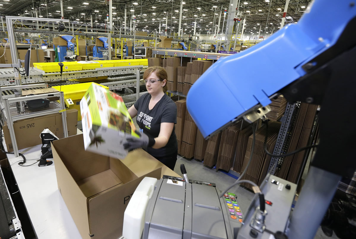 A worker places an item in a box for shipment during a media tour of the new Amazon.com fulfillment center in DuPont. The center is one of 50 around the country and three in the Puget Sound area that process and ship Amazon customer orders using a mix of robotic technology and human employees. (Ted S.