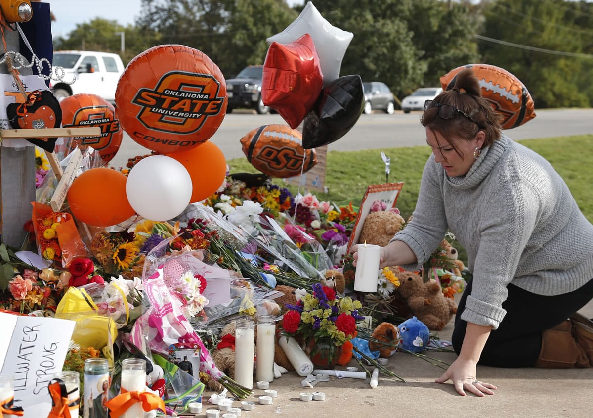 Stefanie Alexander, who witnessed the Saturday homecoming parade crash, places a candle Monday at a makeshift memorial to the victims in Stillwater, Okla.