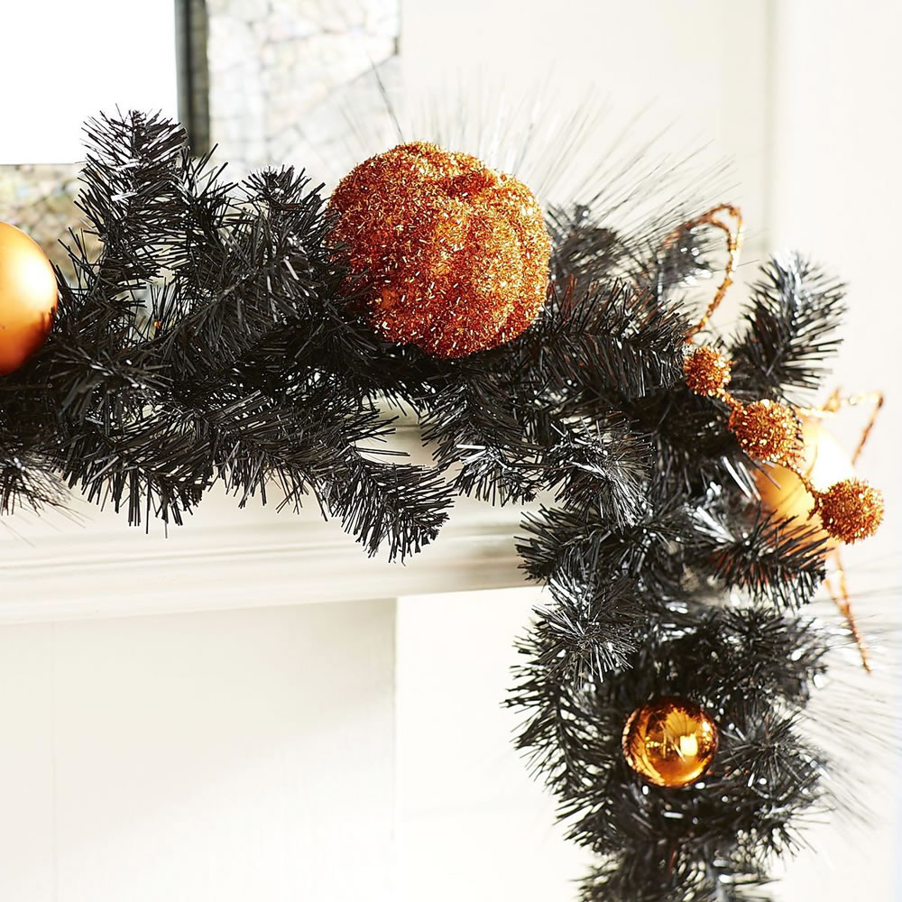 A fun mash-up of seasonal decor, this black pine garland from Pier 1 is embellished with orange pumpkins and ornaments, making it a perfect Halloween mantel or table decoration.