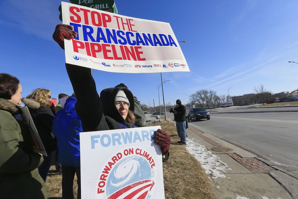 Kelly Kelly of Omaha waves signs with others opposing the Keystone XL oil pipeline during a demonstration outside the office of Rep.