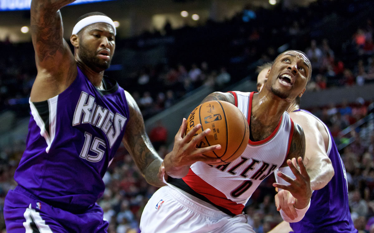 Portland Trail Blazers guard Damian Lillard, right, is fouled by Sacramento Kings center DeMarcus Cousins during the second half of an NBA  preseason game in Portland on Monday, Oct. 5, 2015.