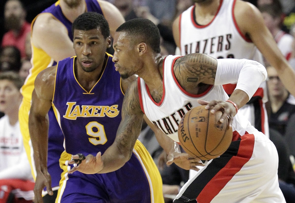 Portland Trail Blazers guard Damian Lillard, right, drives on Los Angeles Lakers guard Ronnie Price during the first half in Portland, Ore., Monday, Jan. 5, 2015. Lillard finished with 39 points in the Blazers' 98-94 win.
