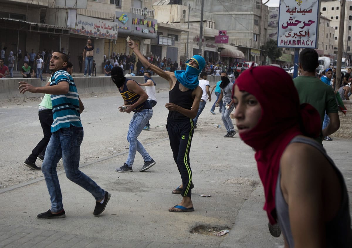 Palestinians throw stones during clashes with Israeli troops at Qalandia checkpoint between Jerusalem and the West Bank city of Ramallah, Tuesday, Oct. 6, 2015.