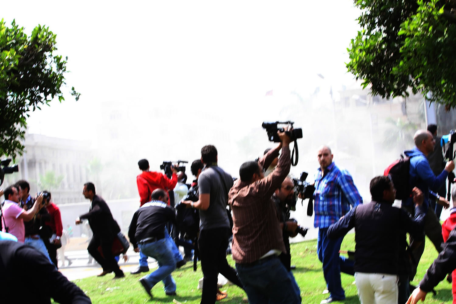Journalists react to an explosion outside of Cairo University on Wednesday, the third of three blasts at the site that targeted security forces and killed a police general.
