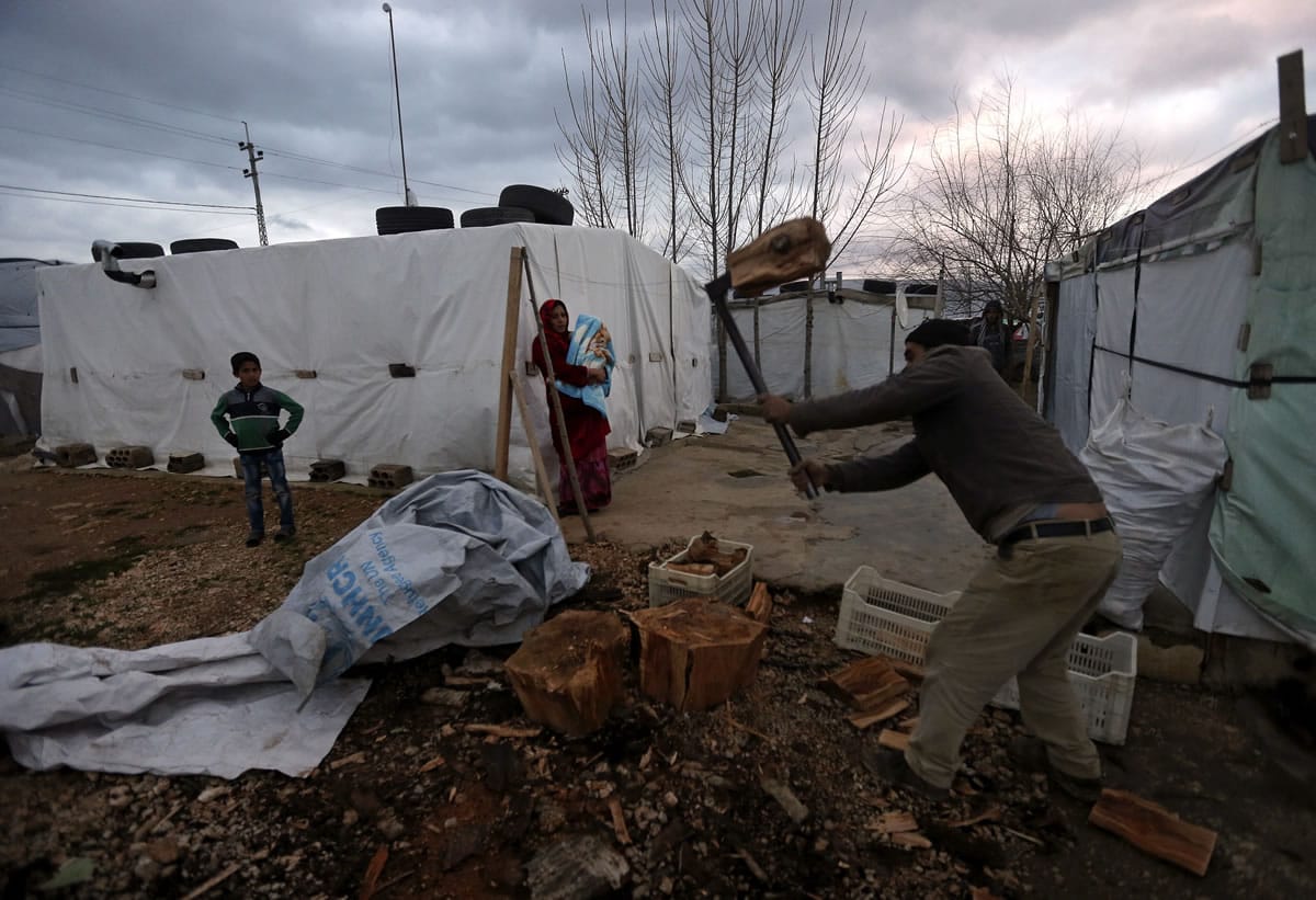 A Syrian refugee, cuts wood as he prepares for the possibility of a snow storm at a Syrian refugee camp, in Deir Zannoun village, Bekaa valley, Lebanon, on Monday.