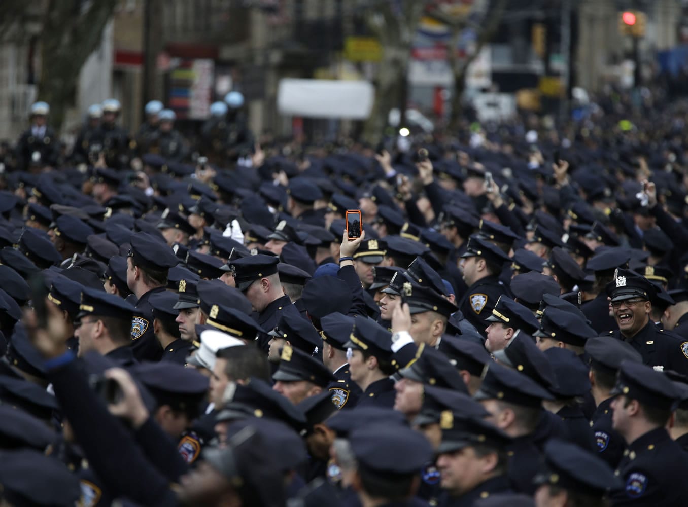 A police officer tries to take a picture above the heads of other police officers Sunday during the funeral of Officer Wenjian Liu in the Brooklyn borough of New York.