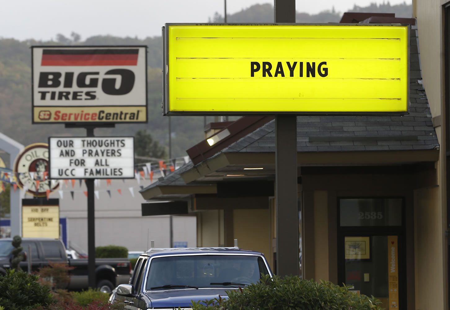 Signs calling for prayers and remembrance for those killed in a fatal shooting at Umpqua Community College, are seen on a pair of local businesses Saturday in Roseburg, Ore.