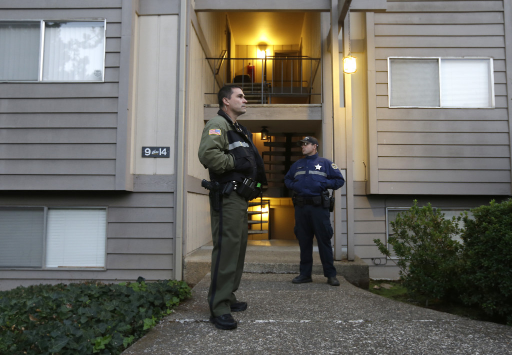 Douglas County Deputy Sheriff Greg Kennerly, left, and Oregon State Trooper Tom Willis stand guard outside the apartment building where alleged Umpqua Community College gunman Chris Harper Mercer lived with his mother in Roseburg, Ore., on Oct. 2. The deadly shooting last week has an eerie parallel with the massacre at Sandy Hook Elementary School that killed 20 pupils and six adult staff members in 2012. Like Adam Lanza, the gunman in the Connecticut massacre, Christopher Harper-Mercer was living a mostly solitary life with a mom who shared his fascination with firearms.