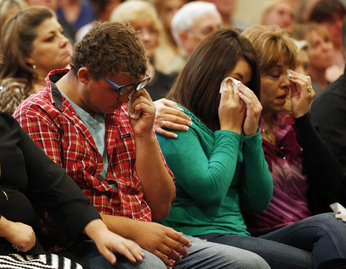 Mathew Downing, who attended Skyview High School in Vancouver, from left, Lacey Scroggins and Lisa Scroggins wipe their eyes during a church service at the New Beginnings Church of God on Sunday in Roseburg, Ore. Mathew Downing and Lacey Scroggins are survivors of the shooting at Umpqua Community College.