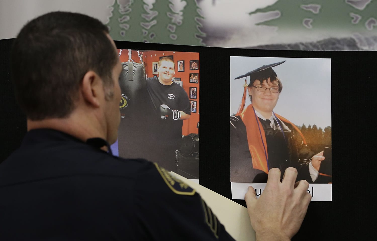 Portland Police Sgt. Pete Simpson places a photo of shooting victim Lucas Eibel, 18, next to a photo of victim Quinn Cooper, 18, for during a news conference, Friday in Roseburg, Ore.