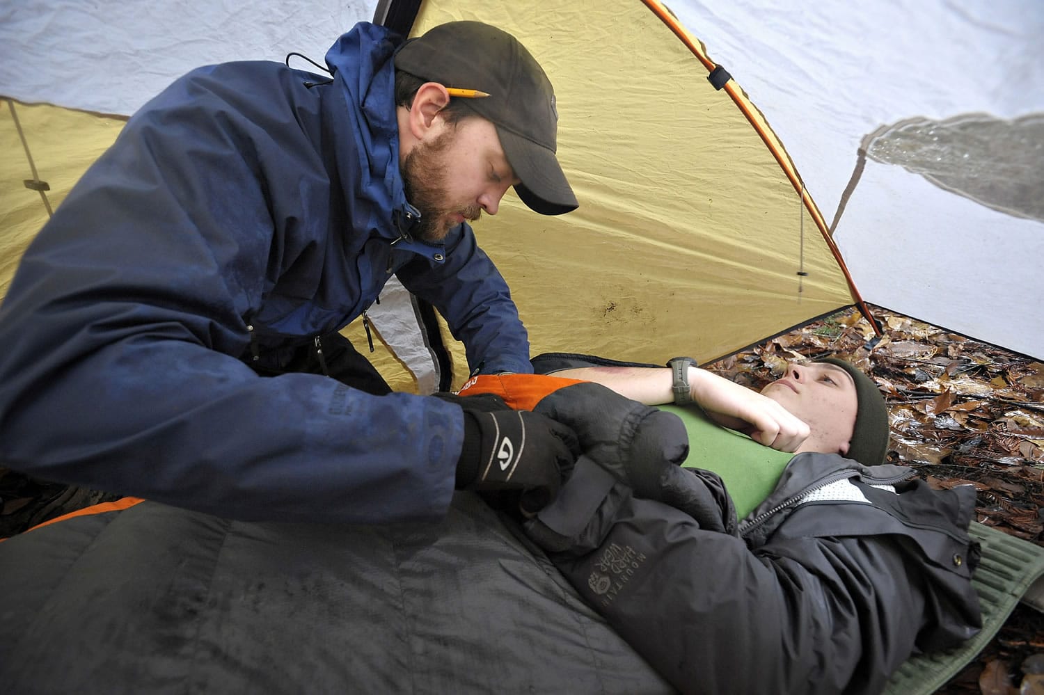 Oregon State University student Ben Church, left, examines fellow student Teddy White, while under a tent during a heavy rain as part of their wilderness first responders class final exam last month in Corvallis, Ore.