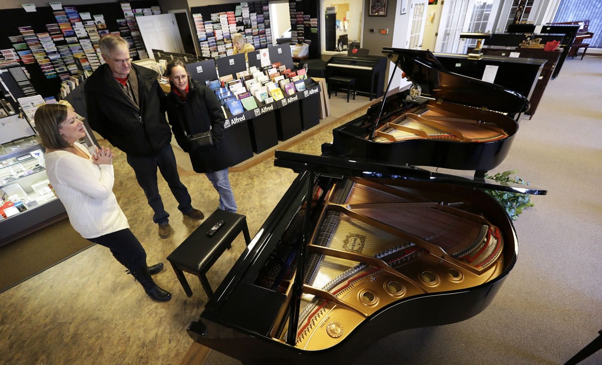 Christi Foster Nunnally, left, shows a grand piano to customers Al and Jill Jorgensen in the Foster Family Music Center piano store showroom in Bettendorf, Iowa.