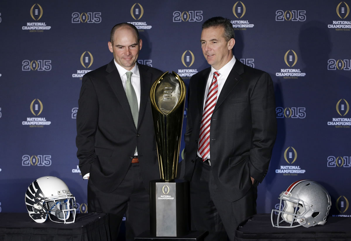 Ohio State head coach Urban Meyer, right, and Oregon head coach Mark Helfrich pose with the championship trophy after a news conference before the NCAA college football playoff championship game Sunday, Jan. 11, 2015, in Dallas. Oregon plays Ohio State in the championship game on Monday. (AP Photo/David J.
