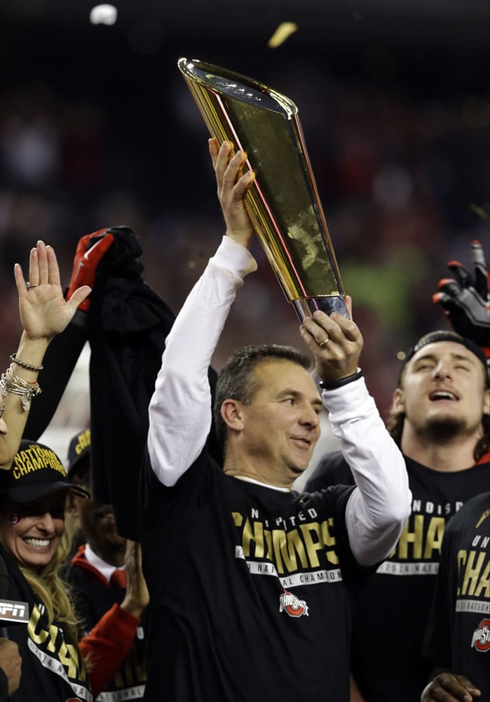 Ohio State head coach Urban Meyer holds up the championship trophy after the NCAA college football playoff championship game against Oregon Monday, Jan. 12, 2015, in Arlington, Texas. Ohio State won 42-20.
